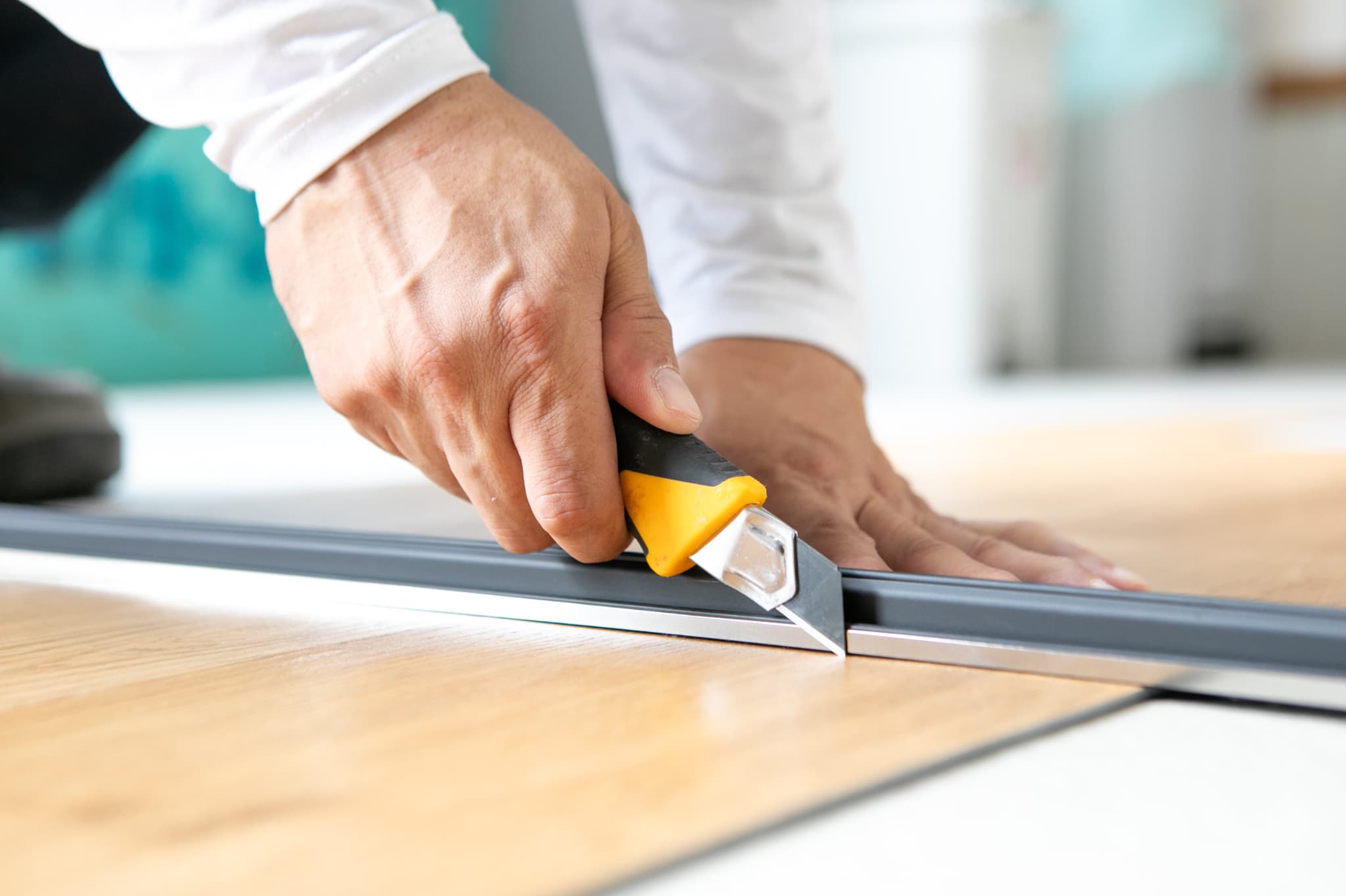 屋根に白の塗装をする作業員の手